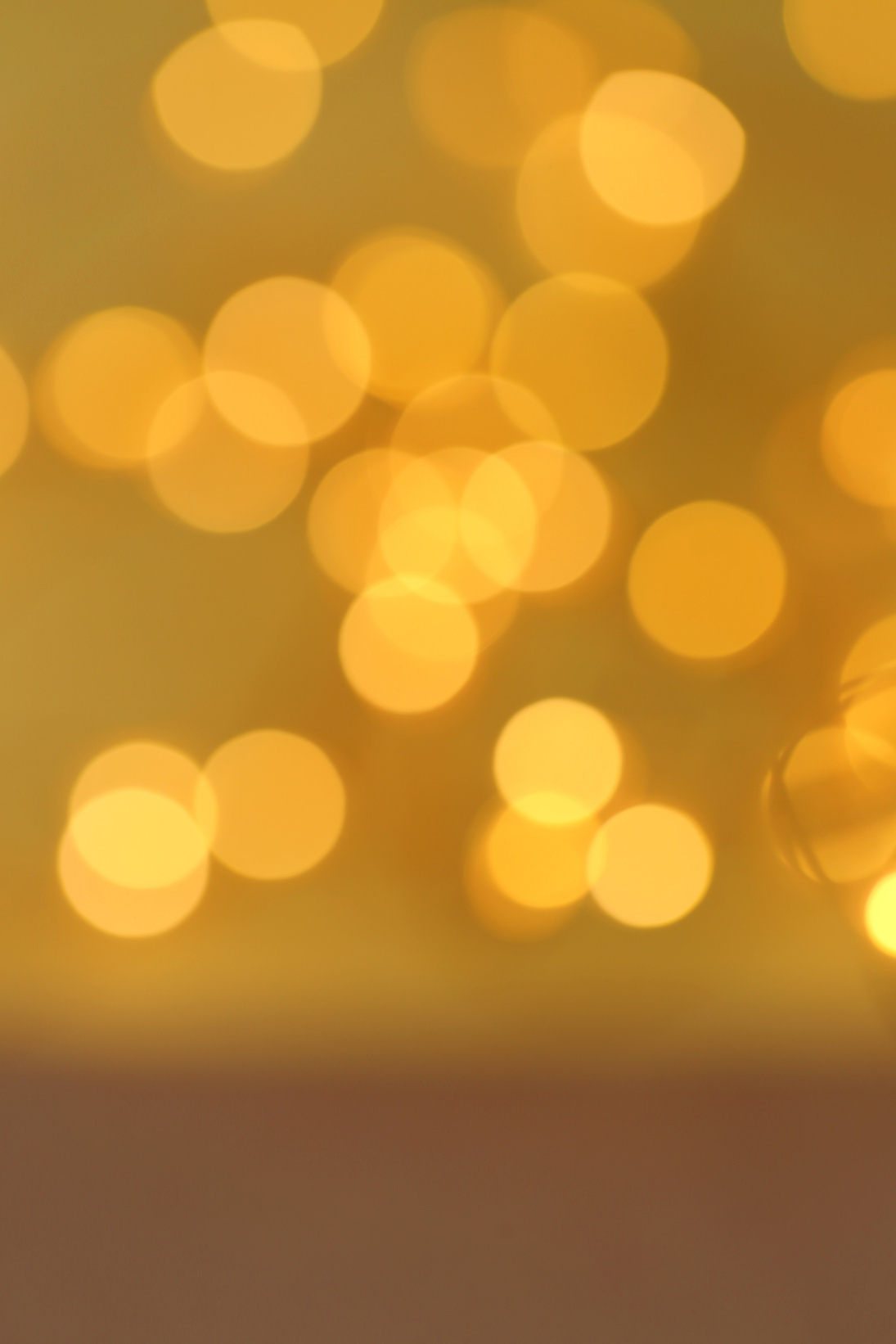 Golden bokeh festive background. glitter brown-gold pattern. Shining background in warm colors. IPhone wallpaper.